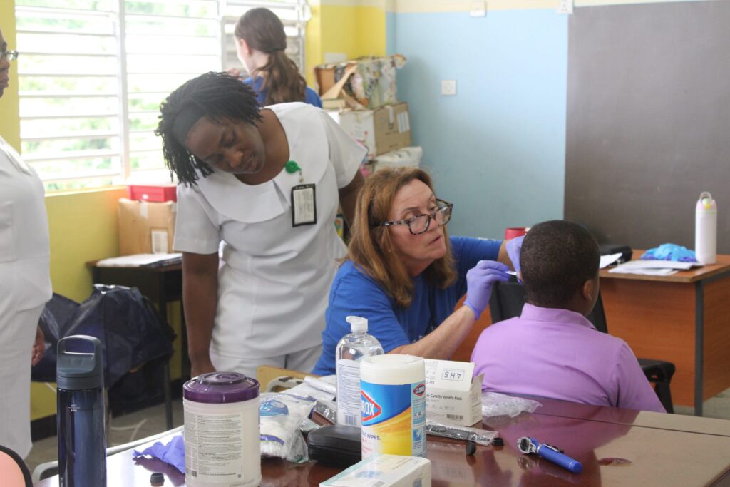 A group observes an ear examination at a desk.