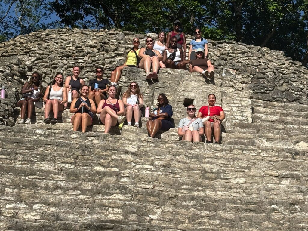 A program group sits on stone steps at an archaeological site.