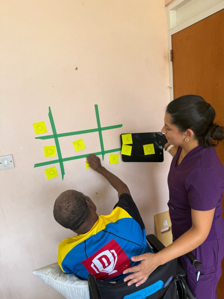 A person supports a participant reaching toward colored squares on a wall.
