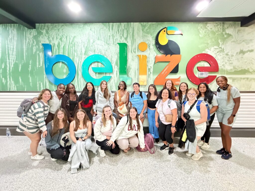 A program group poses beside a Belize sign.