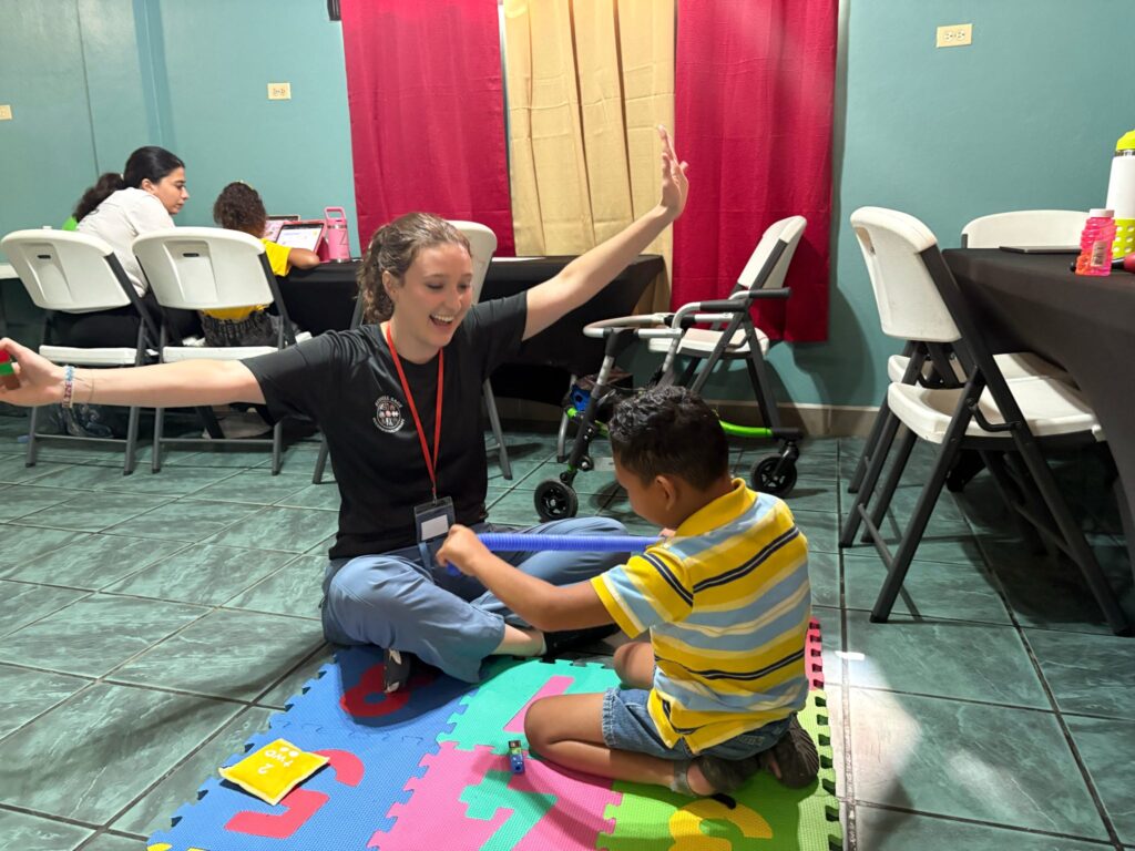 An adult and a child take part in an activity on colorful floor mats.