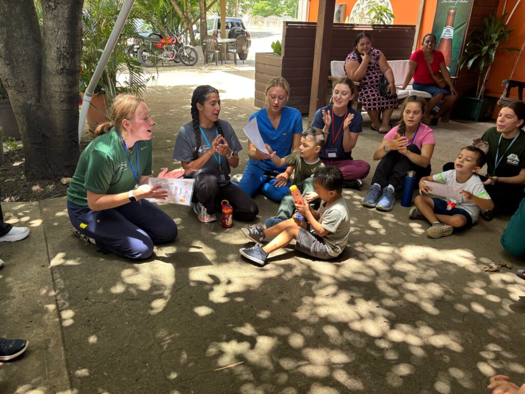 A group watches an outdoor activity from a seated semicircle.