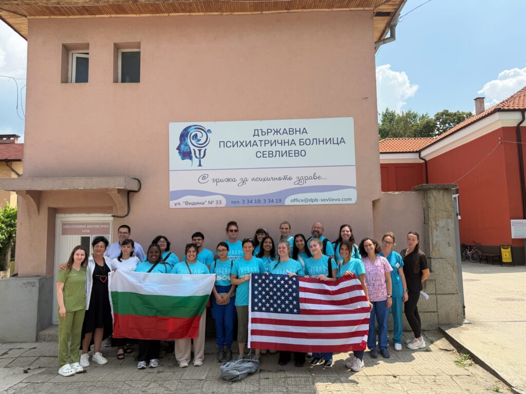 A group holds Bulgarian and United States flags outside a clinic.
